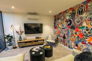 a living room with a large painting on the wall at Funk in the City - Luxury Laneway Apartment with Single Garage in Christchurch