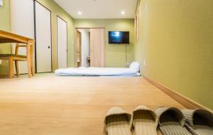 una stanza con un letto e una TV su una parete di HANASTAY花渓居 · 丘（OKA) ad Osaka