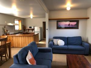 sala de estar con sofá azul y cocina en Seahorse Coastal Villas, en Peterborough