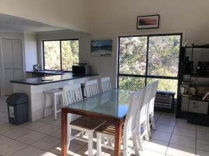 a kitchen with a glass table and white chairs at Tangalooma Holiday House in Tangalooma