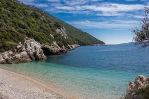 a beach with rocks and water and a mountain at Secluded house with a parking space Tomislavovac, Peljesac - 13280 in Putniković