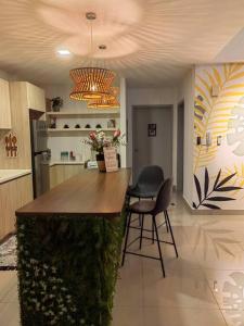 a kitchen with a bar with two chairs and a chandelier at ALOCASIA Geniehome 3BR Free Wifi @ Utropolis Shah Alam in Shah Alam