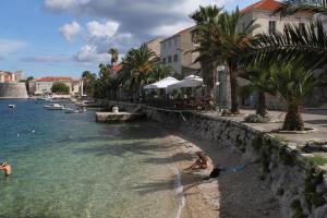 a group of people playing in the water on a beach at Apartments by the sea Korcula - 15689 in Korčula +11 photos