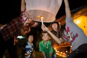a group of people holding up a candle with a child at Phoomtada Homestay in Wiang Pa Pao