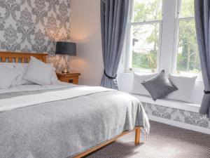 a bedroom with a bed and two windows at Oldfield House in Windermere