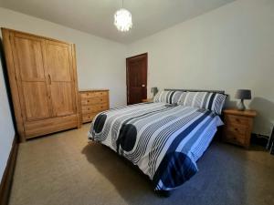 een slaapkamer met een bed en een houten kast bij 2 Mill Street in Penrith