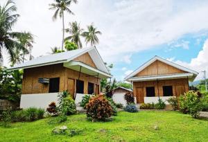 ein Haus in einem Hof mit Palmen im Hintergrund in der Unterkunft Bahandi Beach Lodge in Mambajao