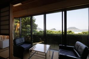 a living room with chairs and a table and a view of the ocean at Mizuno Ryokan in Karatsu