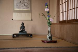 una mesa con una estatua y un jarrón con flores en Mizuno Ryokan en Karatsu