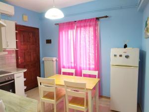 a kitchen with a table and a refrigerator and pink curtains at Als Plomari - Sea View Apartment in Plomari