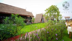 a garden with purple flowers in front of a building at Rice Wonder Cafe & Eco Resort in Rayong