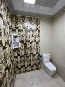 baño con aseo y pared de azulejos en Soft Villa, en Gabala