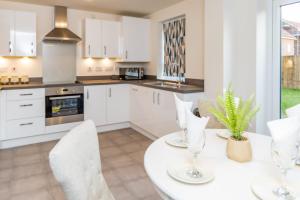 a kitchen with white cabinets and a table with chairs at Stunning 3-Bed Risa House in Beeston Nottingham in Nottingham