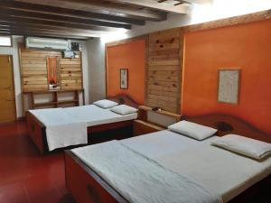 Duas camas num quarto com paredes cor de laranja em Royal Cottage, Anaimalai multiple room em Pollachi