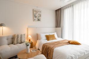 a white bedroom with a bed and a couch at Urbanstay Busan Cityhall in Busan