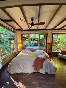 a bedroom with a large bed in a room with windows at Ananda Eco House - Eco Rainforest Retreat in Montville