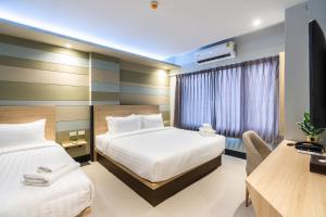 a hotel room with two beds and a desk at Hi Sotel - SHA Plus in Makkasan