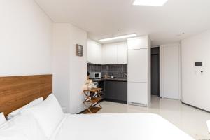 a bedroom with a white bed and a kitchen at Urbanstay Busan Cityhall in Busan