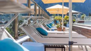 a row of lounge chairs with umbrellas on a roof at MANNI das Hotel in Mayrhofen
