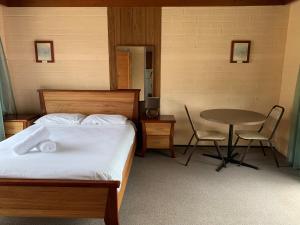 a bedroom with a bed and a table and chairs at Regatta Point Holiday Park in Bermagui
