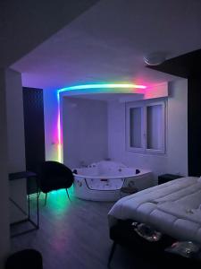 NG SuiteHome - Queven - Balnéo - Netflix - Wifi في Quéven: غرفة مع حوض وغرفة نوم مع أضواء أرجوانية