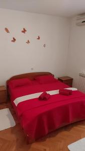a bedroom with a red bed with a red blanket at Apartmani Katatina in Rab