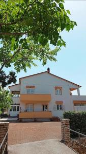 un gran edificio blanco con un árbol delante en Apartmani Katatina, en Rab