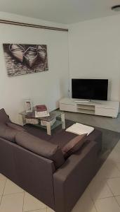 a living room with a couch and a flat screen tv at Apartmani Katatina in Rab