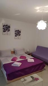 ラブにあるApartmani Katatinaのベッドルーム1室(紫のシーツが敷かれた大型ベッド1台付)