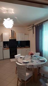 a dining room table with white chairs and a kitchen at Apartmani Katarina in Rab