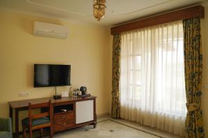 uma sala de estar com uma televisão e uma janela em Sariska Safari Lodge em Thāna Ghāzi
