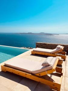 two beds sitting on a patio next to the ocean at Birdhouse Private Luxury Suite in Agios Ioannis Mykonos