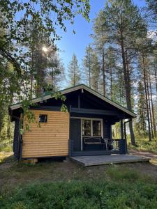 une petite maison dans les bois avec une terrasse couverte dans l'établissement Metsä Kolo, à Saariharju