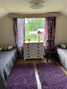 a bedroom with two beds and a dresser with a window at Cottage Elsa in Kuopio