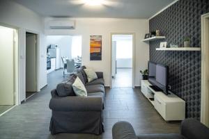 a living room with a couch and a flat screen tv at Olivér 22 Apartman in Fonyód