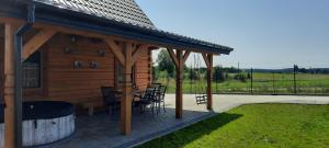 Cette cabane en bois dispose d'une terrasse avec une table et des chaises. dans l'établissement Domek z Bala Brajniki- całoroczny, 