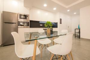 cocina con mesa de cristal y sillas blancas en Apartamento Ribera del Genil Centro, en Granada