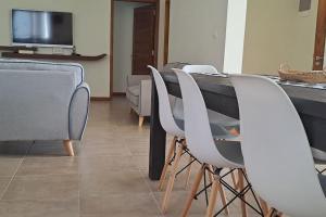 a row of white chairs and a table with a television at Les Villas Thorel in Rivière Noire