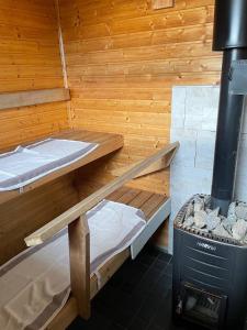two bunk beds in a sauna with a stove at Cottage Elsa in Kuopio