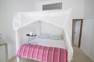 a white bed with a canopy in a room at Le Comfort (self catering) in Anse Royale