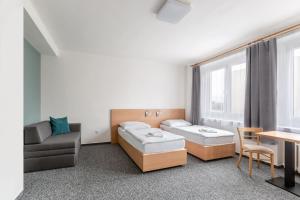Habitación con 2 camas, sofá y mesa. en Hotel Trim, en Pardubice