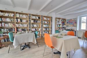 uma biblioteca com duas mesas, cadeiras e livros em Le Temps retrouvé em Concevreux