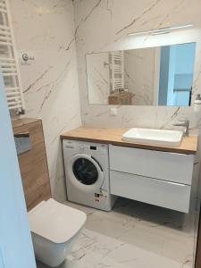 La salle de bains est pourvue d'un lave-linge et d'un lavabo. dans l'établissement AJP Nova3 Lux Apartament, à Szczecin