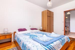 a bedroom with a bed with a blue and white blanket at Apartment Slavica with private Balcony and Parking lot in Punat