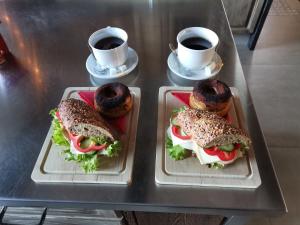 einen Tisch mit zwei Sandwiches und zwei Tassen Kaffee in der Unterkunft Vintage Home Vendégház in Miskolctapolca