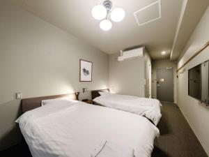 two beds in a room with white sheets at Tabist fami THE GREEN OTARU in Otaru