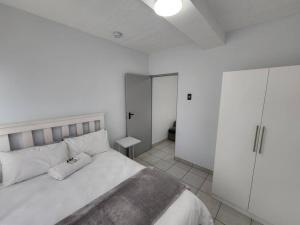 Dormitorio blanco con cama grande y armario en Grace Villas 7, en East London