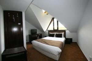 a bedroom with a bed in a attic with a staircase at Pensiunea Clasic in Curtea de Argeş