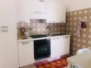 een keuken met witte kasten en een zwarte oven bij Villa Margherita in Alghero