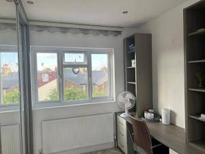 a room with a desk and two windows at Deluxe Homestay near Tottenham Hotspur Stadium in London